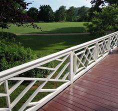 there is a white railing on the side of a building with trees and grass in the background