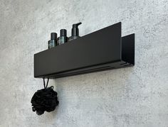 a black shelf mounted to the side of a wall with soap and lotion in it