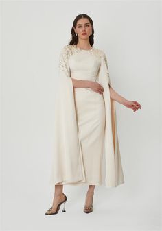 Step into sophistication with this stunning cape sleeve long dress, perfect for making a statement at any special occasion. This dress features a sleek and elegant design, highlighted by exquisite embellishments on the shoulders that add a touch of sparkle and glamour. The flowing cape sleeves create a dramatic yet graceful silhouette, ensuring you stand out in any crowd. Whether you're attending a formal event, wedding, or evening gala, this dress offers timeless elegance with a modern twist. P Fitted Cape Evening Dress For Banquet, Embellished Gown With Cape Sleeves, Embellished Cape Gown For Party, Embellished Cape Dress For Party, Elegant Cape Dress With Sequins, Embellished Cape Evening Dress For Party, Fitted Evening Dress With Cape Sleeves, Elegant Embellished Mother Of The Bride Dress, Wedding Evening Dress With Cape