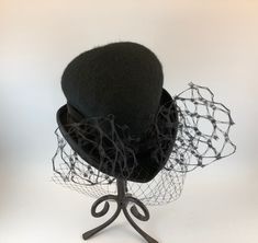 Elegant and whimsical, Makshy's heart shaped cocktail hat adds a touch of sophistication and flair to your formal event attire. Expertly crafted from high-quality wool felt and enriched by a sumptuous silk lining, this refined hat is an indispensable addition for women seeking to enhance their wardrobe with grace. Ideal for various events, including opulent parties, museum visits, or theatrical performances, this captivating vintage hat makes a memorable impression. The distinctive heart shape and delicate veil suit brides, mothers of the bride or groom, and fashion enthusiasts. This versatile fascinator is perfect for cocktail events, charity functions, and social gatherings, with its durable construction ensuring lasting elegance and charm. FEATURES * Expertly crafted and handmade in Gre Handmade Formal Hat With Curved Brim, Formal Handmade Hat With Curved Brim, Handmade Fitted Hats For Formal Occasions, Handmade Fitted Formal Hats, Elegant Fitted Top Hat For Halloween, Formal Fitted Handmade Hats, Handmade Formal Hats, Handmade Adjustable Formal Hats, Elegant Halloween Fascinator