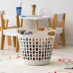 a white laundry basket sitting on top of a rug next to a table and chairs