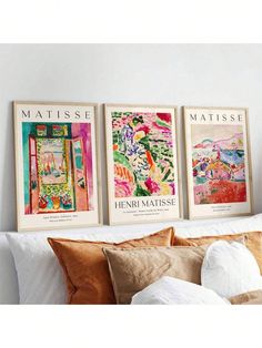 three framed art prints on the wall above a bed with pillows and throw pillows in front of them