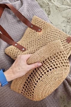 a woman is holding a straw bag on the beach