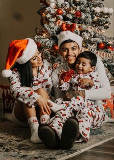 a man and woman in christmas pajamas sitting next to a small child