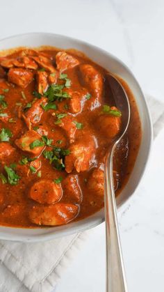 a white bowl filled with meat and sauce