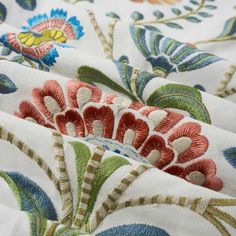 closeup of an embroidered fabric with flowers and leaves on white, red, green, blue, yellow and orange colors