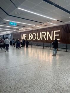 people are walking around in an airport with the word melbourne on it's wall