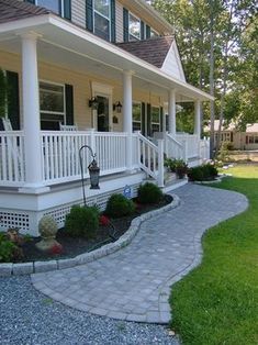 a house with white pillars and green shutters on the front porch is shown in this image