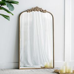 a mirror sitting on top of a table next to candles and a potted plant