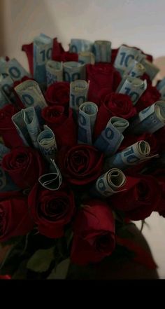 a bouquet of red roses and rolled up twenty dollar bills is shown in this image