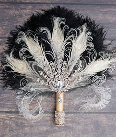 a white and black feather fan on a wooden surface with beads, feathers and pearls