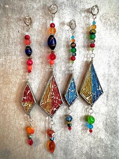 four different colored glass beaded necklaces hanging on a wall