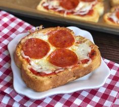 slices of pepperoni pizza on a white plate with a red and white checkered tablecloth