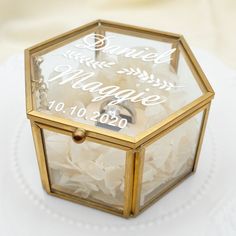 a small glass box filled with white flowers on top of a tablecloth covered table