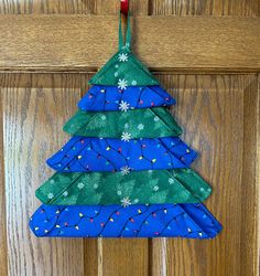 a blue and green christmas tree ornament hanging on a door