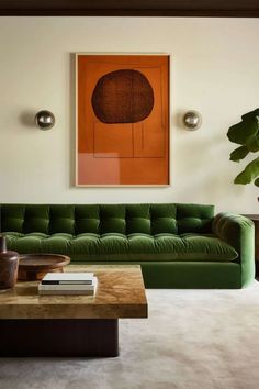 a living room with green couches and a painting on the wall above it's coffee table