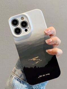 a person holding up a phone case with mountains in the background and trees on it