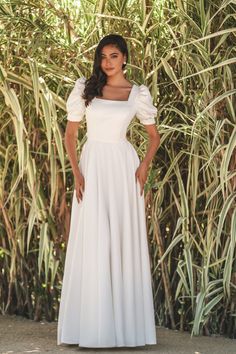 A wedding dress with a classic silhouette has a fitted bodice and flowy skirt with a square neckline and puff sleeves. Square Neck Wedding Dress, Simple Wedding Dress Boho, Sweetheart Bridal, Vintage Wedding Dress Boho, Minimal Wedding Dress, Modest Bridal Gowns, Modest Wedding Gowns, Pink Wedding Dresses, Allure Bridal