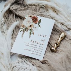 a white card with flowers on it next to a pen and some furnishing