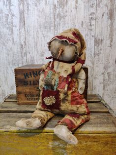 an old teddy bear sitting on top of a wooden box