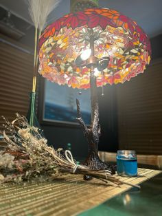 a lamp that is sitting on top of a table next to some branches and feathers