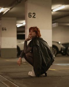 a woman sitting on the ground in a parking garage with her hand under her chin