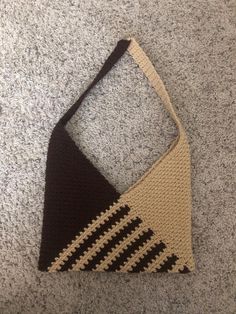 a crocheted triangle bag sitting on the floor