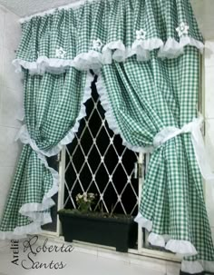 a window with green and white checkered curtains hanging from it's side, next to a potted plant