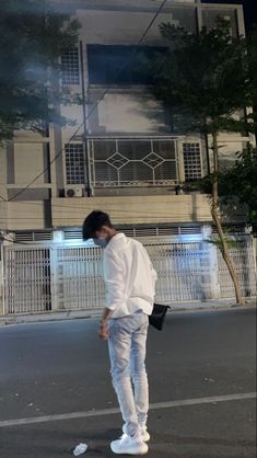 a man standing on the street in front of a building with white walls and windows