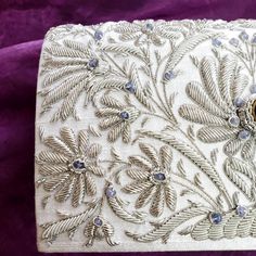 "OOAK Statement bridal clutch. Look stunning wearing this white silk clutch hand embroidered with metallic silver flowers, including central lotus flowers and embellished with amethyst stone and scattered aqua chalcedony stone beads. The lotus flower is the symbol of rebirth and new beginnings, as it emerges pure white from the waters in which it grows. Perfect symbol for a wedding! Something blue? Got it! Wear this on your special day and for years to come. This is a piece meant to be cherished Luxury White Clutch For Reception, Silver Hand Embellished Evening Bag For Formal Occasions, Formal Silver Hand Embellished Evening Bag, Formal Silver Hand-embellished Evening Bag, Silver Embellished Evening Bag For Wedding, Elegant Silver Evening Bag With Handwork, Traditional Silver Embroidered Evening Bag, Formal Embroidered Silver Evening Bag, Silver Hand Embellished Clutch Evening Bag