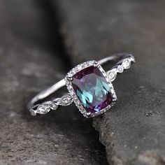 a ring with an amethorate and diamonds on it sitting on top of a rock