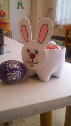 an easter egg sitting on top of a table next to a paper bunny