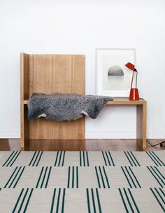 a wooden bench with a blanket on top of it next to a lamp and pictures