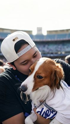 a man holding a dog in his arms at a baseball game