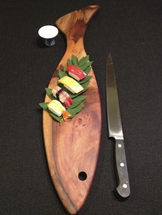 a wooden cutting board with sushi on it next to a knife