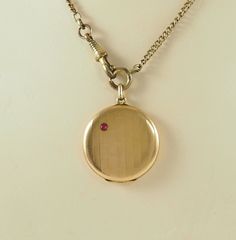 A delightful antique Edwardian period gold filled circular locket in rose gold tone. The front with a brushed finish with a single ruby, 3mm in diameter, the ground imitating bamboo(?). The reverse with the bamboo pattern. Opening directly at  the bail. With space for two photographs with both frames and plastic coverings. The chain is for display only. Germany 1900-1910. 7.6g The space for photographs 2.5cm in diameter. In inches 1". The locket 3.1cm in diameter.   In inches 1 1/4". With bail 4 Antique Screw Back Jewelry For Formal Occasions, Victorian Yellow Gold Jewelry With Screw Back, Historical Yellow Gold Jewelry For Wedding, Historical Yellow Gold Wedding Jewelry, Victorian Yellow Gold Locket Necklace For Formal Occasions, Formal Rose Gold Engraved Locket Necklace, Formal Rose Gold Locket Pendant Necklace, Formal Rose Gold Locket Necklace, Rose Gold Locket Necklace For Formal Occasions