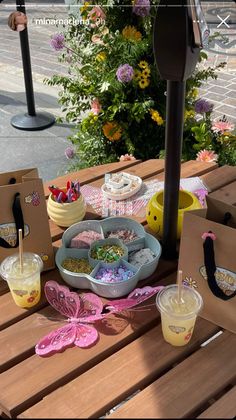 an outdoor picnic table is set up with cupcakes and desserts on it