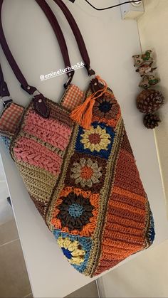 a multicolored crocheted bag hanging from a hook on a white wall