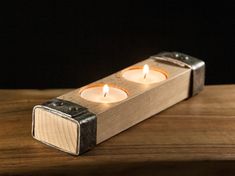 two lit candles sitting on top of a wooden table