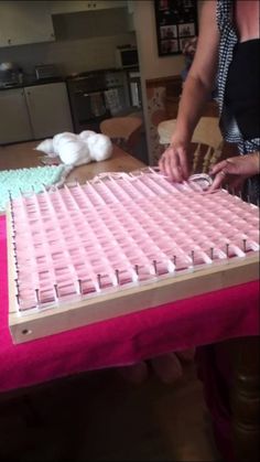 a woman is cutting up a cake with pink icing on it's side