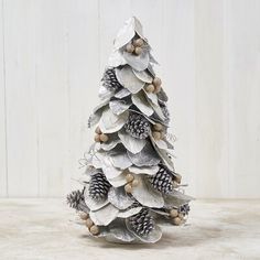 a white christmas tree made out of silver tinsel and pineconis on a table