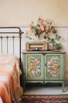 an old fashioned dresser with flowers on it next to a bed