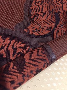 a close up view of a tie on a tablecloth with white and brown patterns