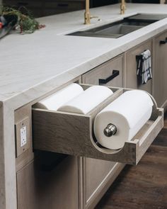 two rolls of toilet paper are hanging from the pull out drawer in this modern kitchen