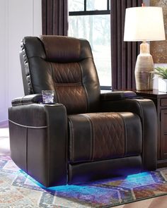 a brown recliner chair sitting on top of a rug next to a table with a lamp