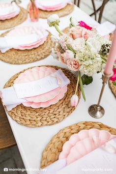 a table topped with plates and flowers on top of a white table cloth covered table