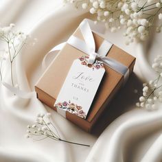 a brown box with a white ribbon and some baby's breath flowers