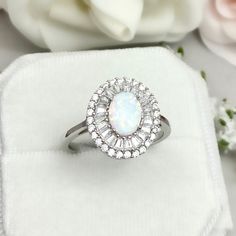 This beautiful ring is made from genuine 925 sterling silver with rhodium plating. Ring details- -The Main stone is an oval cut 8mm by 6mm Lab Created White Fire Opal Stone -Side stones are 2mm by 1mm Baguette simulated diamonds and Round 1.2mm Simulated Diamonds -Ring is casted in solid 925 sterling silver with rhodium plating (yellow gold and rose gold plated also available, please check the drop down menu for more options) -The Total face height of the ring measures 11mms and the band width m Luxury Sterling Silver Oval Opal Ring, Sterling Silver Baguette Cut Wedding Rings, Luxury Silver Opal Promise Ring, Silver Wedding Ring With Baguette Cut, Silver Oval Crystal Ring With Halo Design, Silver Wedding Rings Baguette Cut, White Gold Opal Ring With Cubic Zirconia, Cubic Zirconia Opal Promise Ring, Oval Shape, Elegant Silver Opal Ring With Cubic Zirconia