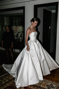 a woman in a white dress is walking through the room