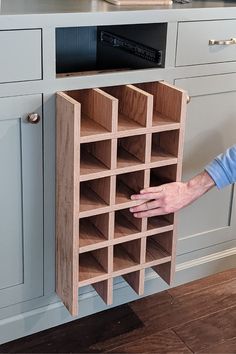 a man holding a wooden wine rack in his hand while standing next to a kitchen counter